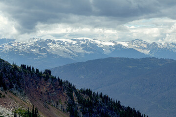 Fototapeta premium Majestic mountain range with snow-capped peaks under a cloudy sky, Blackcomb Gondola. Whistler, BC, Canada