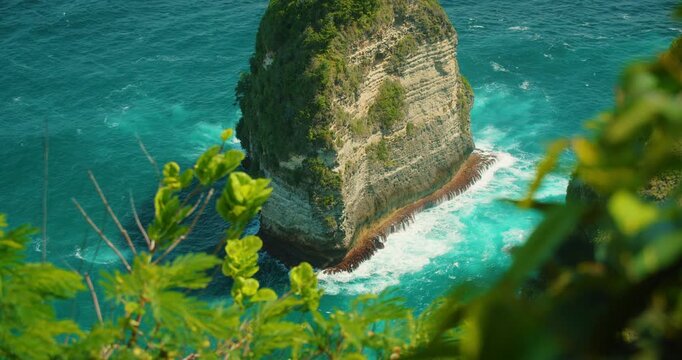 Isolated limestone rock tower stands in blue sea water in Bali Nusa Penida