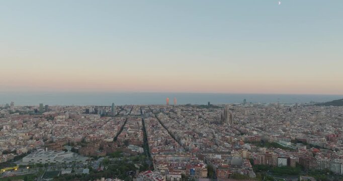 Cinematic aerial of Barcelona city skyline. Drone fly over Eixample residential famous urban grid and Sagrada Familia cathedral with morning sunrise cityscape. Catalonia, Spain. Travel Destination.