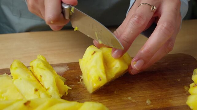 Slicing fresh juicy pineapple with a kitchen knife, in kitchen counter top