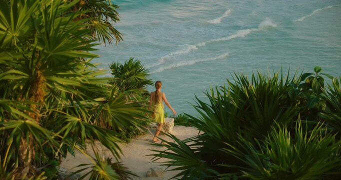 Traveler woman walks down coastal path near Playa Santa Fe waves in Tulum Mexico