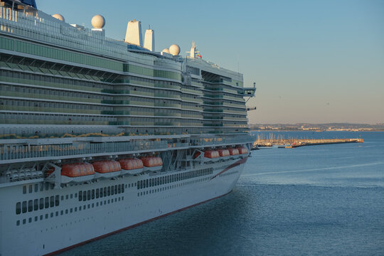 Massive gigantic modern cruiseship cruise ship liner Iona or Arvia in Cadiz, Spain during summer Mediterranean cruising with harbor and container port infrastructure