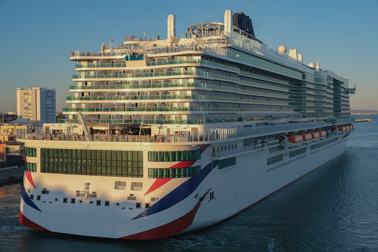 Massive gigantic modern cruiseship cruise ship liner Iona or Arvia in Cadiz, Spain during summer Mediterranean cruising with harbor and container port infrastructure