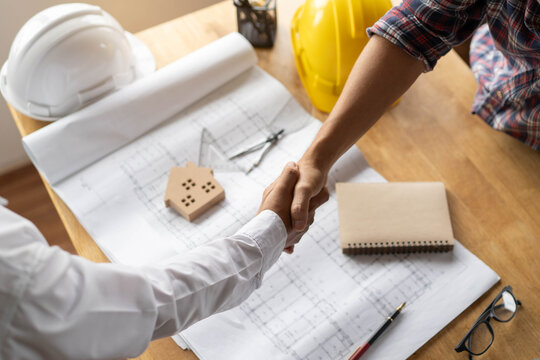 Client shaking hands with contractor after confirm blueprint to renovate house.