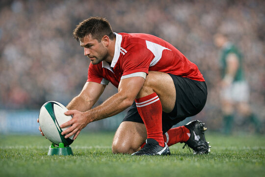 A rugby player holding a ball on the field, getting ready for the game. This scene captures the intensity of the sport and the focus of the player.