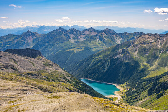 Lake Neves sits at the end of Molini Valley in South Tyrol, Italy, nestled among the Zillertal Alps. This scene showcases the lake's blue waters and the surrounding mountains.