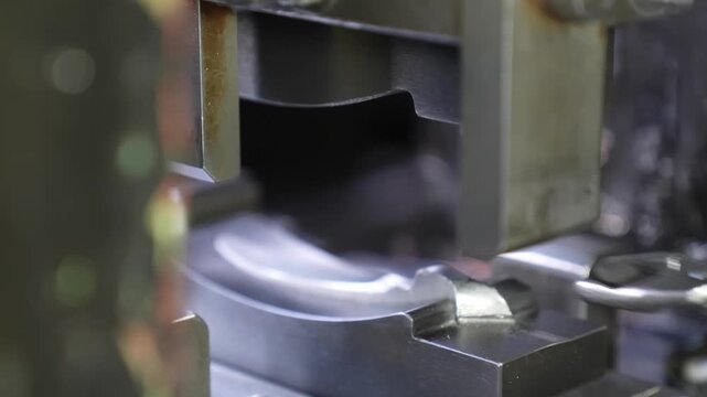 Close up of an empty curved steel forging die cavity on a press machine