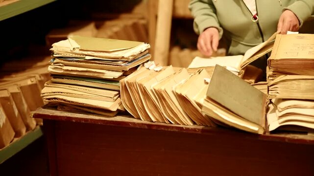 Archivist Sorting Stacks Of Vintage Paper Files On Desk In Archive. Historical Documentation
