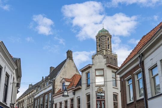 Zwolle, Netherlands: Beautiful historic street view featuring old Dutch facades and the prominent Onze Lieve Vrouwetoren (De Peperbus) against a bright blue sky.