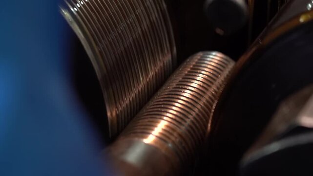 Continuous close up of helical threads being rolled onto a brass toned rod