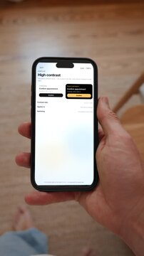 The same screen is shown twice, once standard and once in high contrast accessibility mode. Point of view shot in vertical format with the phone held in the hand. Useful for designing for everyone.