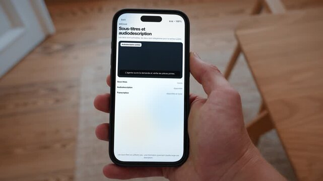 A video player shows captions turned on with audio description available as an option. Point of view shot with the phone held in the hand. Useful for making media accessible.