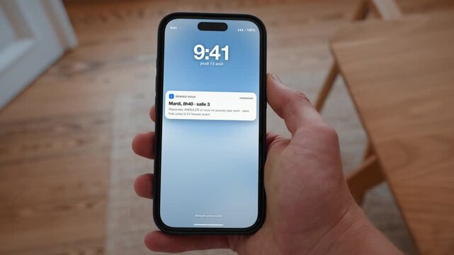 An appointment reminder appears on the lock screen with an option to cancel or confirm. Point of view shot with the phone held in the hand. Useful for never missing an appointment.
