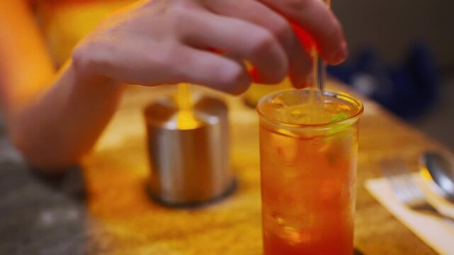 Woman stirring refreshing fruity cocktail drink