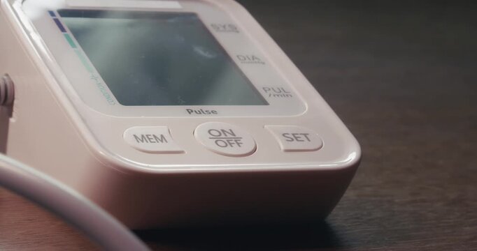 Close-up of a digital blood pressure monitoring device activated by finger touch during a routine home self-care procedure.