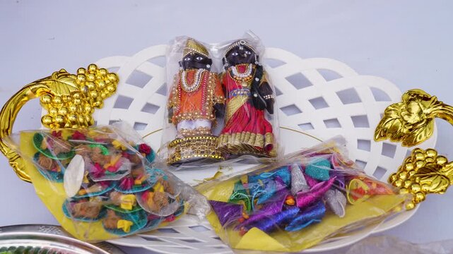 South Indian wedding white basket holds miniature bride and groom dolls and colorful wrapped gifts in close-up slow motion.