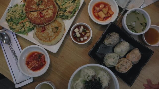 Traditional Korean meal featuring large mandu, pajeon and various Korean side dishes served together as a dining spread in South Korea - top view