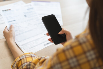 Bill pay concept. Online internet banking asian young woman hand hold invoice use mobile smart...