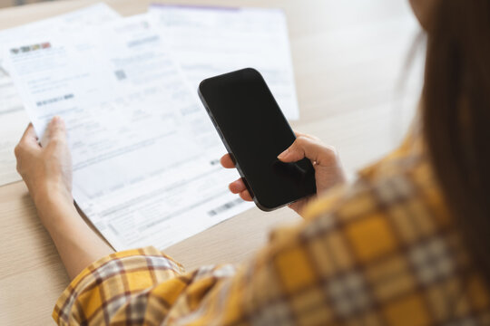 Bill pay concept. Online internet banking asian young woman hand hold invoice use mobile smart phone spend scan barcode to transfer to pay money of credit card without cash. Technology of financial