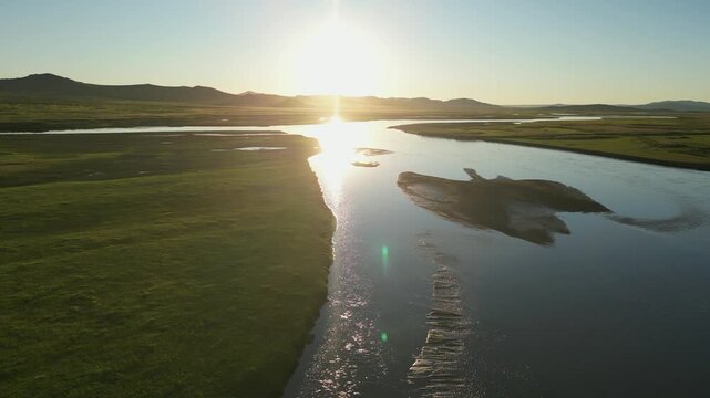 Aerial flight into setting sun over Tuul River on vast Mongolian steppe