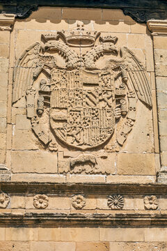 Weathered carved stone coat of arms with crowned double headed eagle and heraldic relief on a historic facade in Baeza, Andalusia, Spain