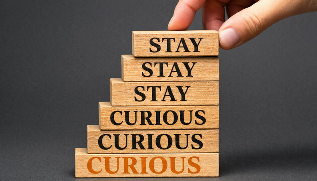 Hand placing wooden block with stay curious text on staircase of blocks concept for personal growth and lifelong learning