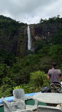 Man taking photos of majestic Diyaluma waterfall with camera in Sri Lanka.