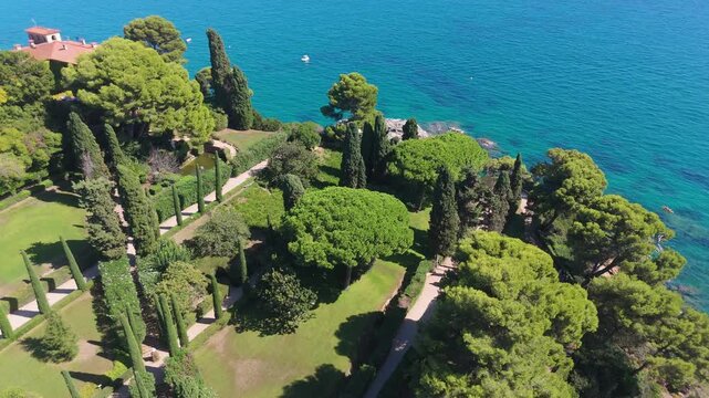 An aerial view of a drone flies from Santa Clotilde Park over the beach and coastal cliffs on a sunny day in the tourist town of Lloret De Mar, Catalonia, Spain.