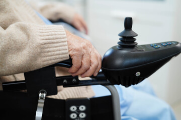 Asian elderly disability woman patient use joystick electric wheelchair in hospital. © manassanant