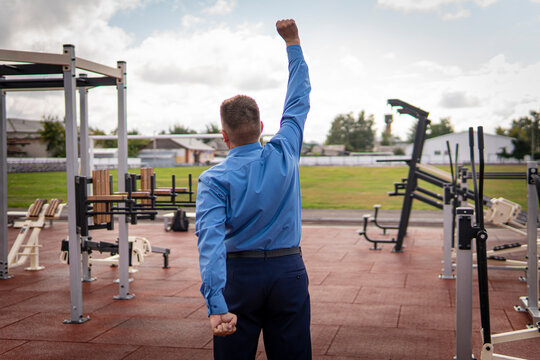 Handsome young man in a black suit, white shirt and tie training in gym