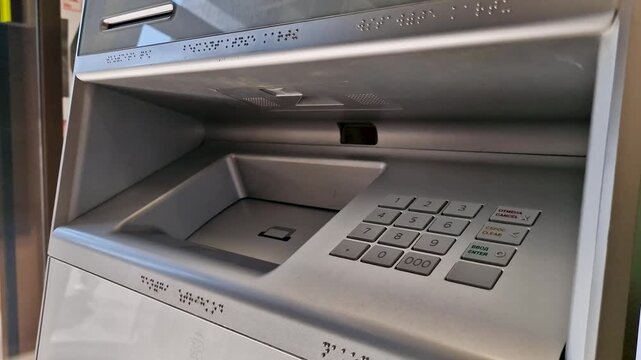Close-up view of a woman inserting paper money currency banknotes into an automated teller machine (ATM) cash acceptor slot
