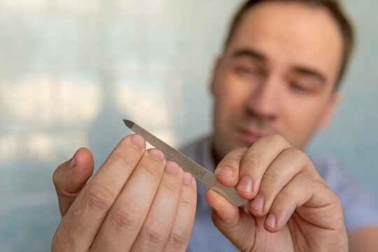 Man using a nail file. man cuts his own nails with scissors on a blue background.