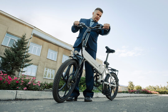 A new modern alternative mode of transport. Eco-friendly electric bike. businessman take his bicycle from parking