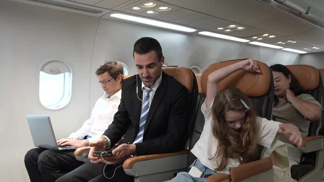 A business trip features a male businessman working on his laptop, and next to him sits a business father and his daughter on the plane. This is the airline industry.
