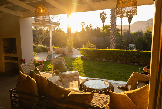 elderly man in beautiful outdoor patio overlooking vast garden and mountains at sunset