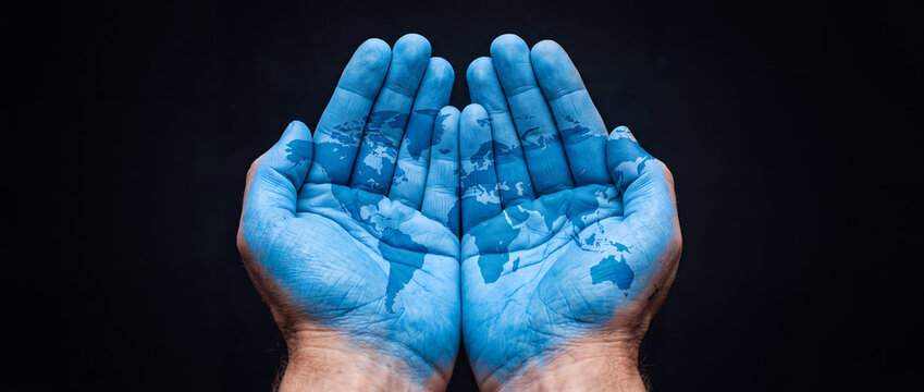 World Map Painted on Cupped Hands Against Black Background