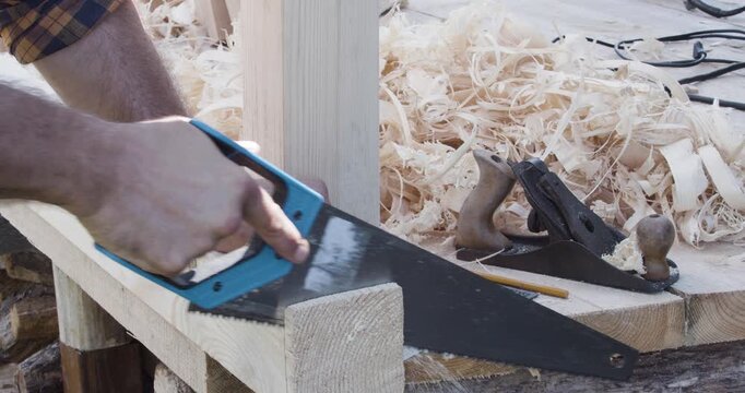 A skilled carpenter's hands expertly maneuver a handsaw, cutting through a sturdy board. This video captures the precision and dedication involved in woodworking.