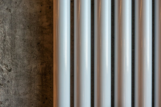 Modern tubular radiator sections on raw concrete wall