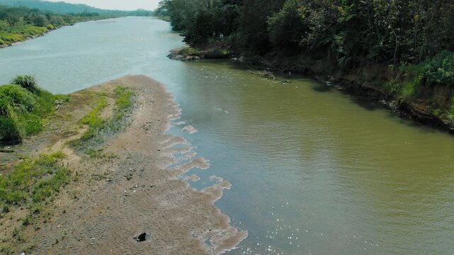 Green landscape surrounds wide flowing waters of famous Tarcoles River with flowing crocodile in Costa Rica