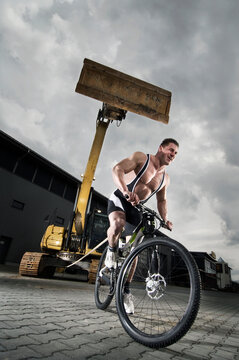 Strong Cyclist pulls huge excavator with mountainbike