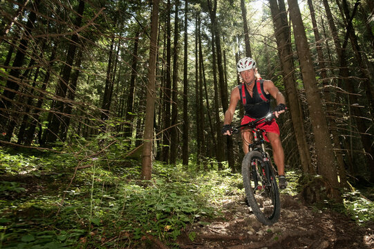 Mature man mountain biking on a trail through the woods