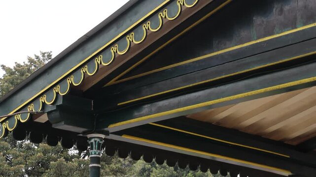 Green and yellow trim adorns a traditional rooftop. White walls contrast with vibrant, wavy decorative moldings. Roof tiles stretch above the painted border