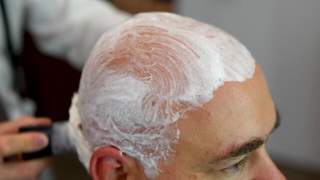 Barber applying shaving cream on man's head