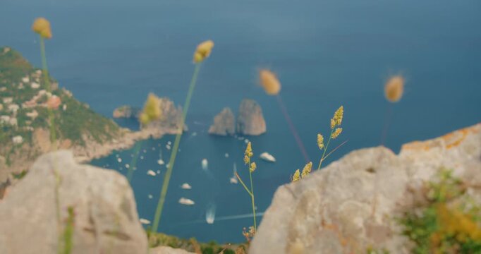 Scenic view of Capri cliffs above the sea with distant Faraglioni stacks in summer day