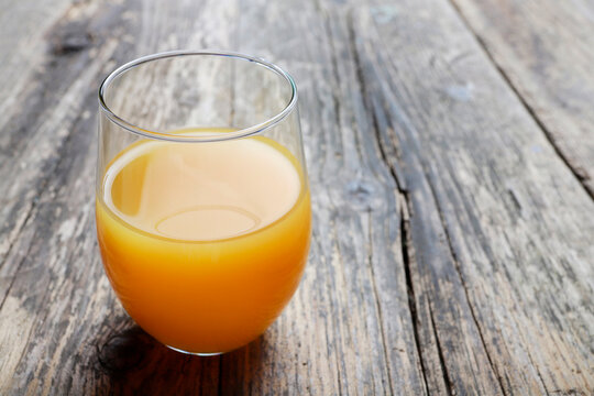 Glass of orange juice on wooden table, copy space.