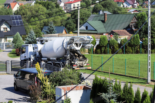 ZAKOPANE, POLAND - AUGUST 28, 2026: A concrete mixer truck driving through a narrow road between rural houses in the Podhale region.