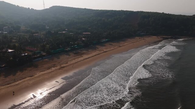 Aerial view rotating backwards over waves at Kudle Beach in Gokarna, India