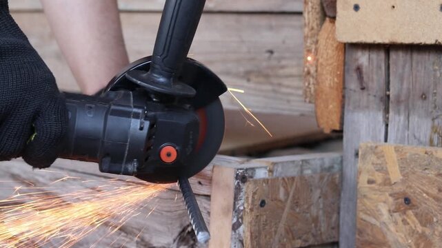 Worker cuts metal reinforcement with an angle grinder, repair work, hand tools, construction, cordless tool, cordless grinder. Cutting metal with a grinder with sparks. Professional power tool