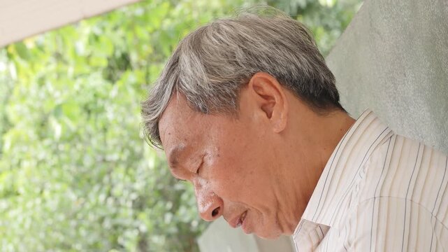sad southeast asian senior man with grey hair doing facepalm gesture in a sunny park, real silver generation elderly side profile view