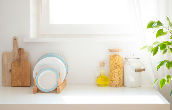 Kitchen counter interior with wooden cutting boards, stacked plates, olive oil jug, pasta jar and enamel can